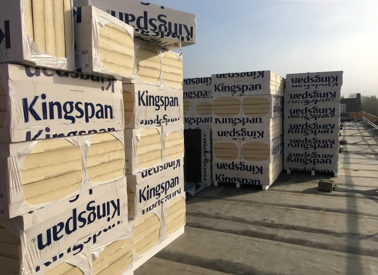 Gestapelde pakketten Kingspan isolatieplaten op een plat dak, klaar om te leggen